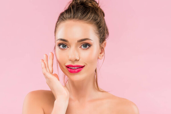 naked beautiful woman with pink lips posing with hand near face isolated on pink 