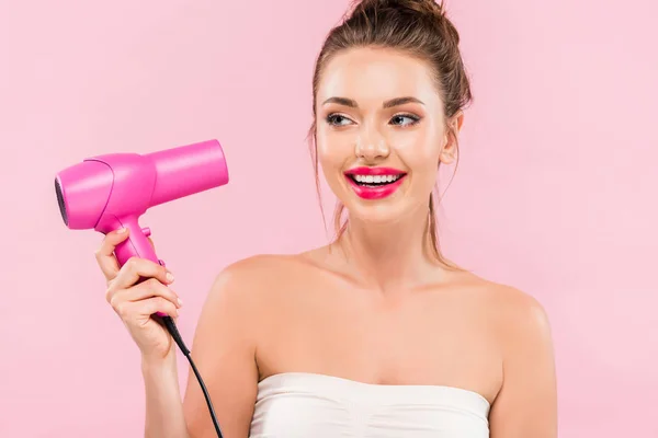 Uśmiechnięta Piękna Kobieta Różowymi Ustami Trzymająca Suszarkę Włosów Odizolowana Różowo — Zdjęcie stockowe