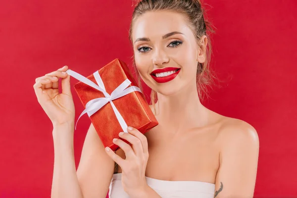 笑容可亲的漂亮女人 红唇上挂着礼品盒 与红色隔离 — 图库照片