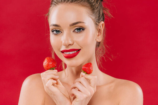 улыбается голая красивая женщина с красными губами держа клубнику изолированы на красный
