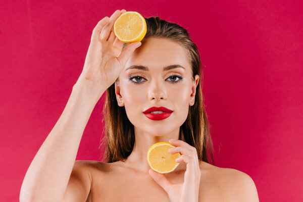 nude beautiful woman with red lips holding orange halves isolated on burgundy