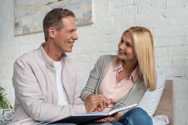 Leende Par Med Anteckningsbok Håller Händerna Sängen — Stockfoto