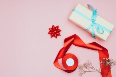 Çiçeklerle, kurdelelerle ve pembelerle izole edilmiş Noel hediyelerinin üst görüntüsü.
