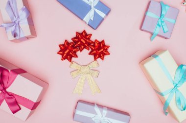 Pembe üzerinde izole edilmiş, kurdeleli ve fiyonklu Noel hediyeleri kutuları.