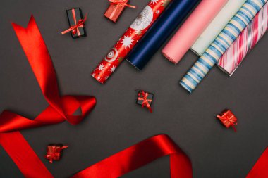 Kağıt ruloların, kurdelelerin ve siyah üzerine küçük hediye kutularının üst görünümü