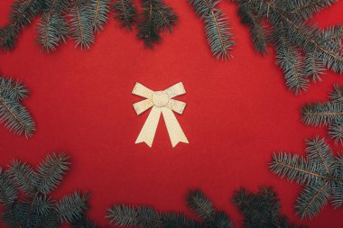 Ladin dalları ve kırmızı üzerinde altın fiyonk olan noel çerçevesinin en üst görüntüsü