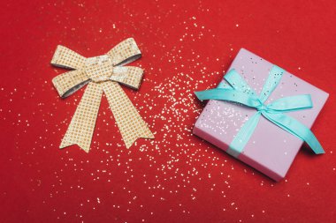 Altın yaylı ve kırmızı üzerine konfetili bir Noel hediyesinin en üst görüntüsü