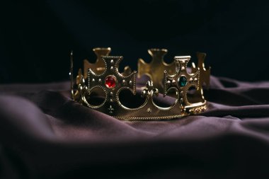 retro golden crown with gemstones on black cloth clipart