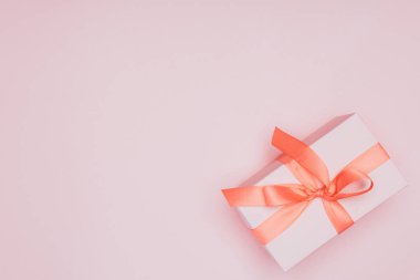 Pembe renkte izole edilmiş, kurdeleli Noel hediyesi kutusunun üst görüntüsü.