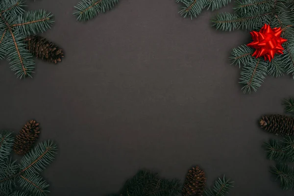 Spruce Dalları Çam Kozalakları Siyah Üzerine Kırmızı Fiyonk Olan Noel — Stok fotoğraf