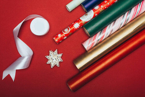 top view of wrapping paper rolls, ribbon and bows on red