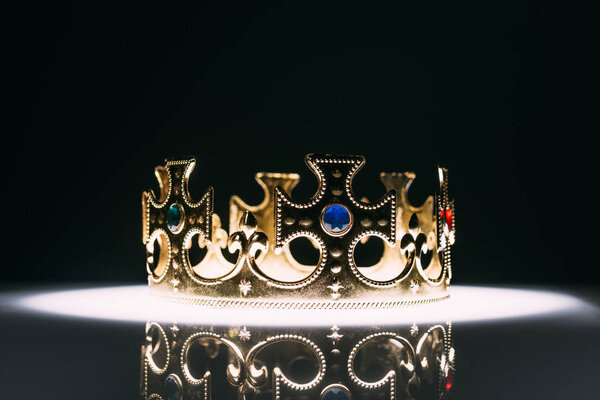 золотая корона с драгоценными камнями на черном
