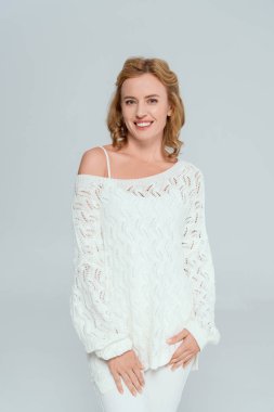 Gri renkli kameraya bakan çekici ve gülümseyen bir kadın. 