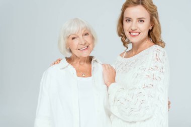 Çekici kız gülümseyen anneye sarılıyor ve gri renkli kameraya bakıyor. 