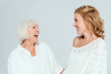 Çekici bir anne ve gülümseyen bir kız. Gri üzerinde izole edilmiş birbirlerine bakıyorlar. 