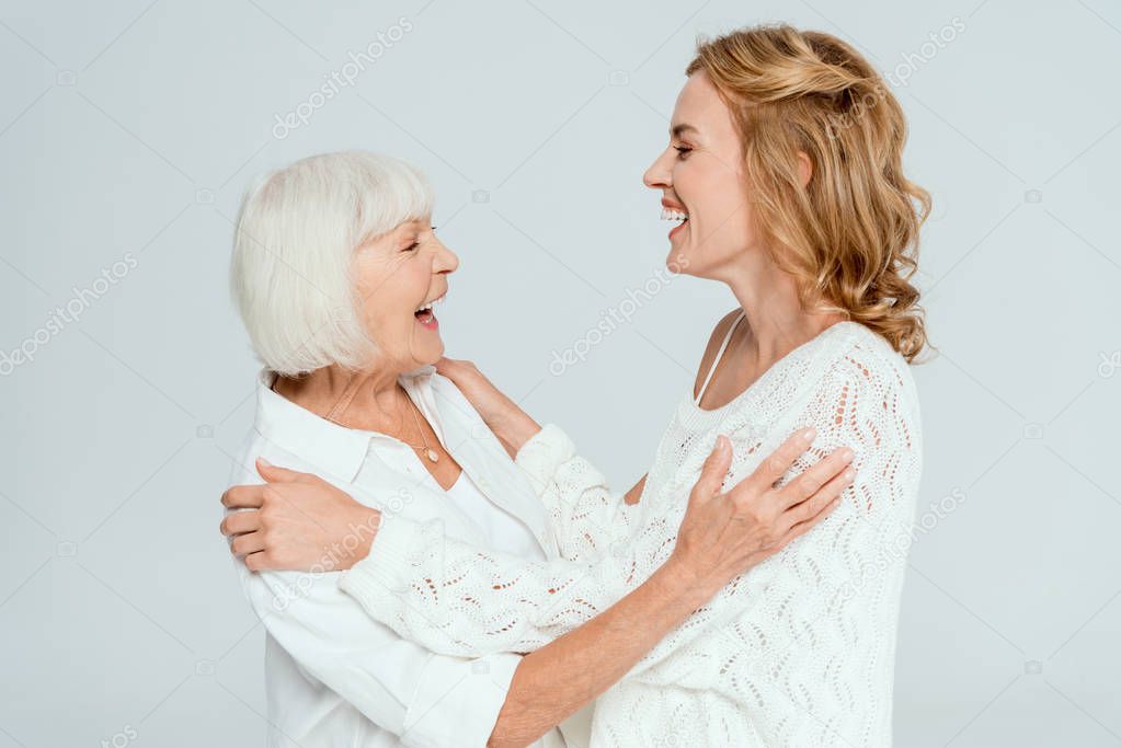 attractive mother and smiling daughter hugging isolated on grey 