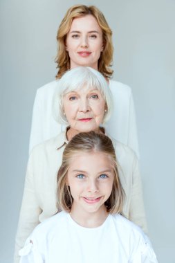 Gülümseyen torun, büyükanne ve anne Gri üzerine izole edilmiş kameraya bakıyor 