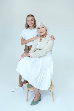 Gülümseyen torun gri arka planda büyükanneye sarılıyor. 