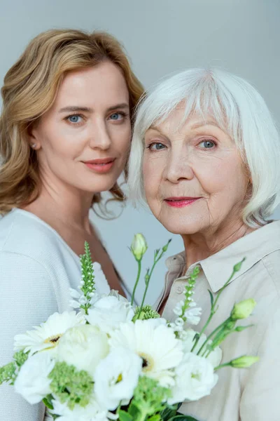 Lächelnde Tochter Und Mutter Mit Blumenstrauß Schauen Vereinzelt Die Kamera — Stockfoto