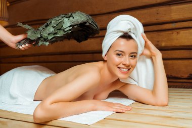 cropped view of woman hitting her friend with birch broom in sauna  clipart
