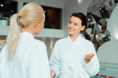 Beyaz bornozlu, kaplıcada konuşan çekici ve gülümseyen arkadaşlar. 