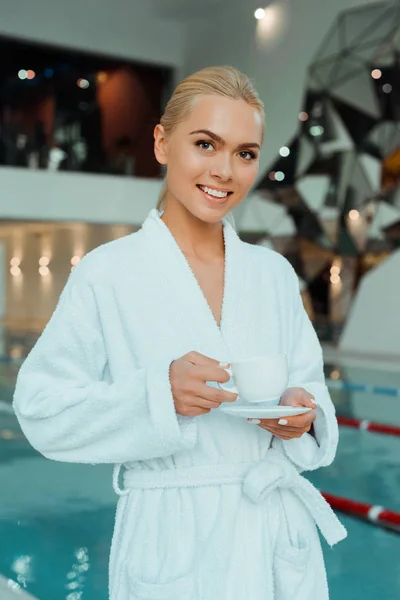 穿着白色浴衣的迷人而微笑的女人 在温泉里端着一杯咖啡 — 图库照片