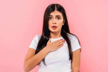 Eli göğsünde pembe tenli, esmer, endişeli bir kız.