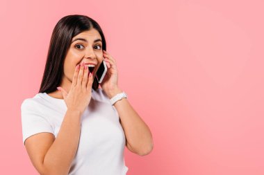 Heyecanlı, güzel, esmer bir kız. Akıllı telefondan konuşuyor. Pembelerden izole edilmiş.