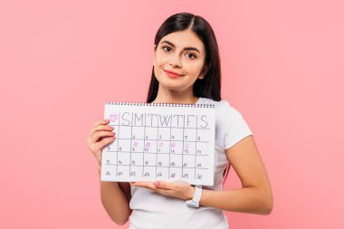 smiling pretty brunette girl holding period calendar isolated on pink clipart