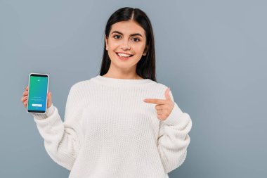 Kyiv, Ukrayna - 20 Eylül 2019: gri renkli twitter uygulaması ile akıllı telefonu işaret eden beyaz kazaklı güzel esmer kız