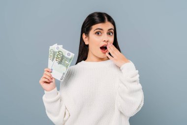 Beyaz kazaklı güzel bir kız elinde euro banknotları tutuyor. Gri üzerine izole edilmiş.