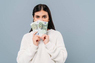 Beyaz kazaklı güzel bir kız avroya yakın banknotlar tutuyor.