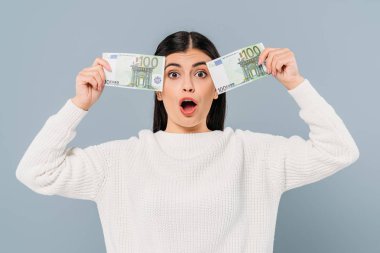 Gri renkli banknotlar tutan beyaz kazaklı güzel kız şaşırdı.