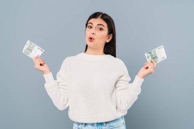 Gri renkli banknotlar tutan beyaz kazaklı güzel kız şaşırdı.