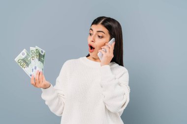 Beyaz kazaklı, elinde euro banknotları olan ve gri renkli telefondan konuşan güzel bir kız.