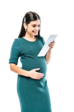 Gülümseyen hamile bir kız beyaz üzerinde izole edilmiş fetal ultrason görüntülerine bakıyor.