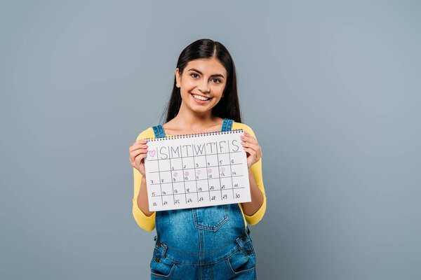 smiling pregnant pretty girl holding period calendar isolated on grey