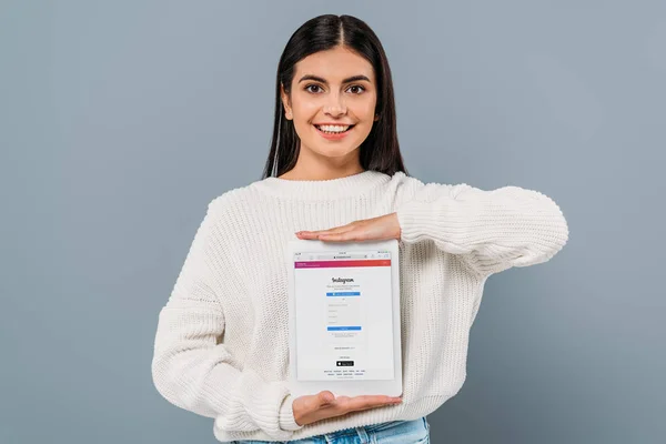 Kyiv, Ukrayna - 20 Eylül 2019: Gri renkli Instagram uygulaması ile elinde dijital tablet tutan beyaz kazaklı güzel esmer kız