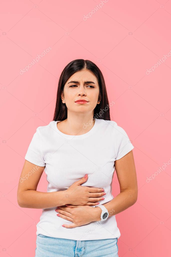 pretty brunette girl suffering from stomachache isolated on pink