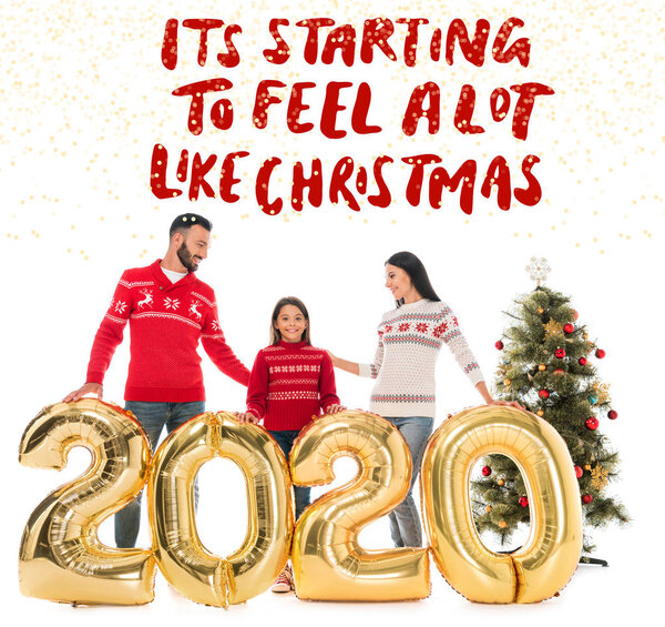 счастливая семья в свитерах, стоящих возле воздушных шаров и рождественской елки изолированы на белом с его начинает чувствовать себя много, как рождественская иллюстрация
