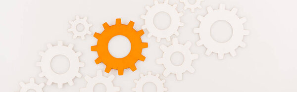 top view of one orange gear among another isolated on white, panoramic shot