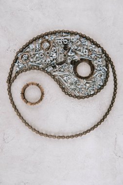 top view of aged metal gears and screws arranged in taijitu symbol on grey background clipart