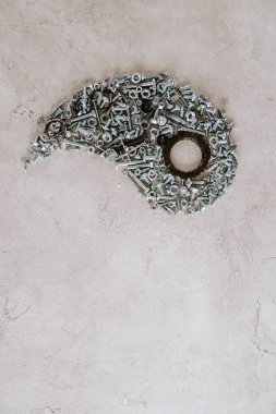 Gri arkaplanda Taijitu sembolünün bir kısmına yerleştirilmiş eski metal vidaların üst görünümü