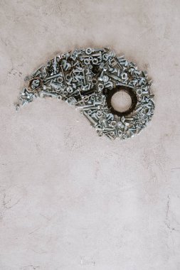 top view of aged metal screws arranged in part of taijitu symbol on grey background clipart