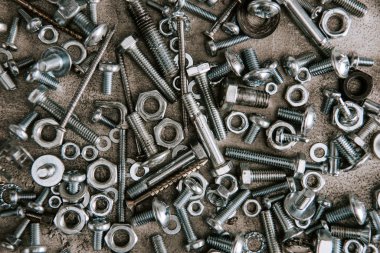 top view of metal screws and nails scattered on grey background clipart
