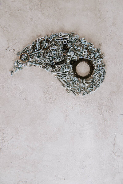 top view of aged metal screws arranged in part of taijitu symbol on grey background
