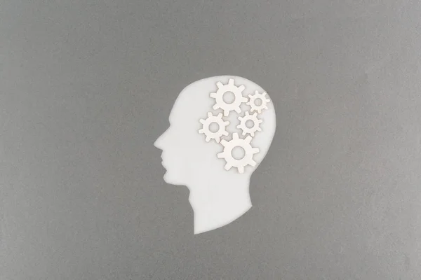 top view of cut out white human head with gears isolated on grey