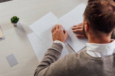 Masasında kopya alanı olan körler alfabesi yazı tipi okuyan kör adamın genel görünümü
