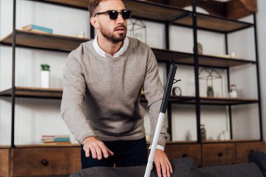 Koltuk ve oturma odasındaki kör adamın yanındaki bastonun seçici odağı.