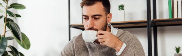 Panoramic shot of blind man drinking coffee at home